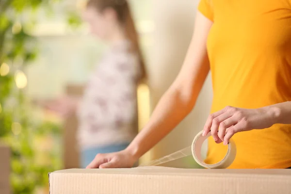 Young girl sealing cardboard box — Stock Photo, Image