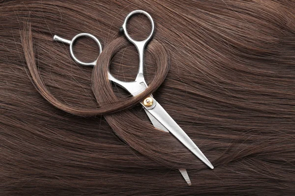 Hairdresser's scissors with dark brown hair — Stock Photo, Image