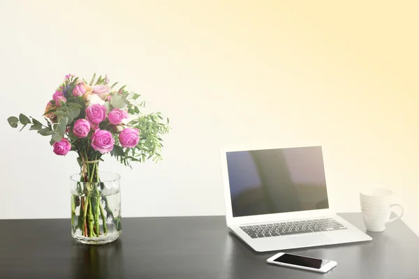 Tarro de rosas al lado del portátil — Foto de Stock