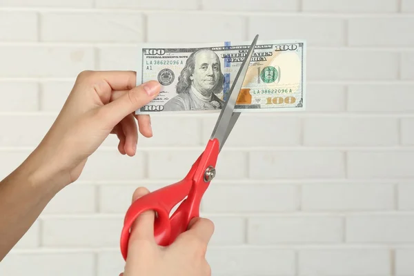Manos con tijeras cortando dinero — Foto de Stock