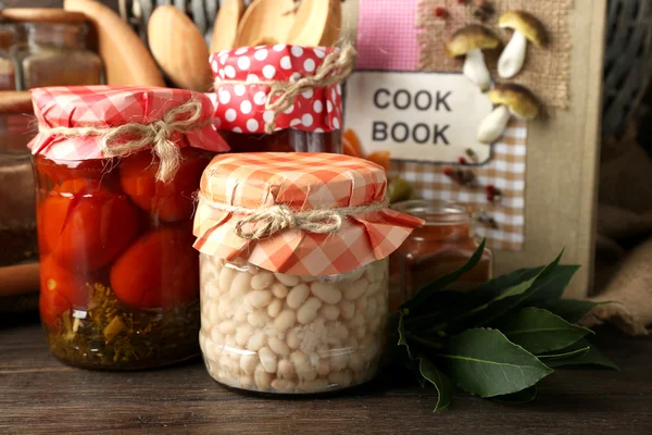 Kavanoz turşu sebze, fasulye, baharatlar ve ahşap arka plan üzerinde mutfak eşyaları — Stok fotoğraf
