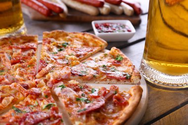 Pizza ve bira cam ahşap masanın üzerine dilimlenmiş, yakın çekim