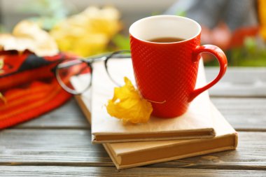 Kırmızı kitap, ekose ve ahşap masa üzerinde sonbahar yaprakları yığını çay fincan