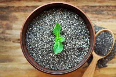 Chia tohumu nane ile kase ahşap arka plan üzerinde bırakır