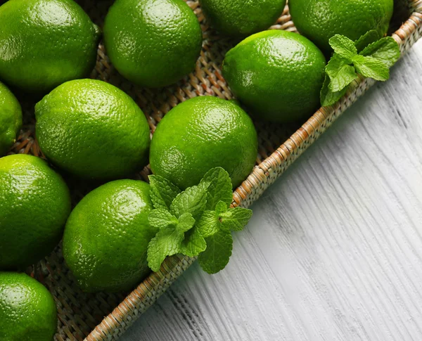 Wicker basket of limes on table — Stock Photo, Image