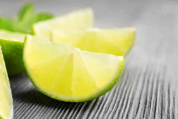 Slices of lime and mint on wooden background — Stock Photo, Image