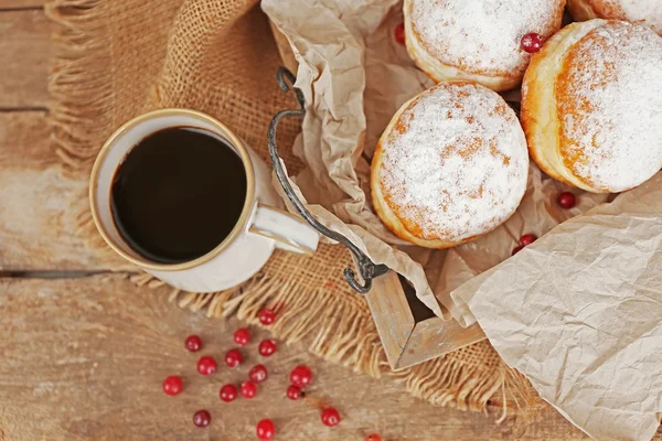 Deliciosas rosquillas azucaradas con grosella roja en bandeja de madera con pergamino de primer plano —  Fotos de Stock