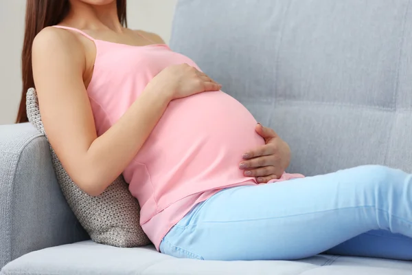 Gravid kvinna vilar på soffa — Stockfoto