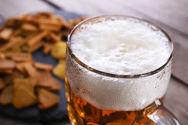 Caneca de cerveja e lanches na mesa de madeira — Fotografia de Stock