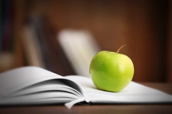 Apple e livro aberto na mesa — Fotografia de Stock