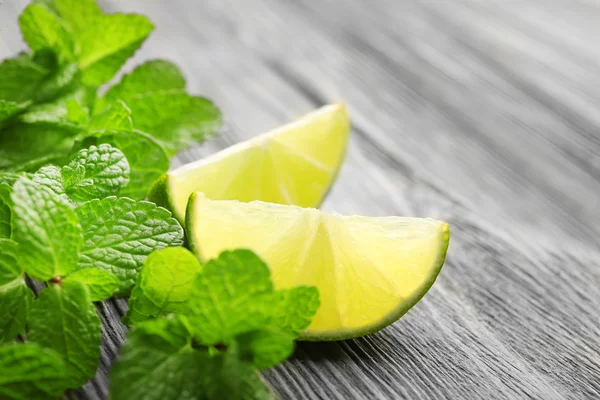 Slices of lime and mint on wooden table — Stock Photo, Image