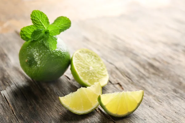 Limas frescas con menta, sobre mesa de madera —  Fotos de Stock