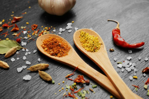 Verschillende kruiden en lepels op houten tafel — Stockfoto