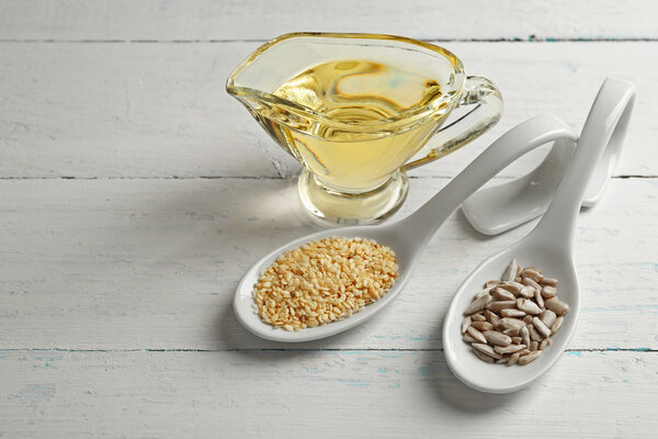 Flax and sunflower seeds with oil on wooden table