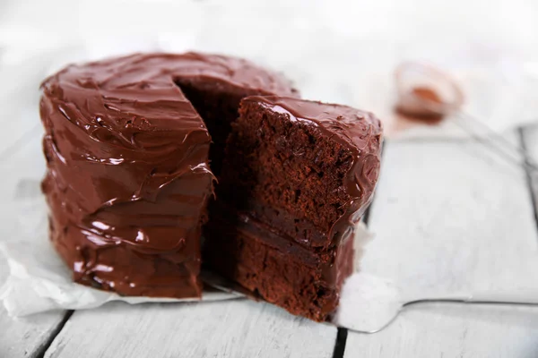 Chocolate cake with a cut piece on wooden table background, closeup — Stock Photo, Image