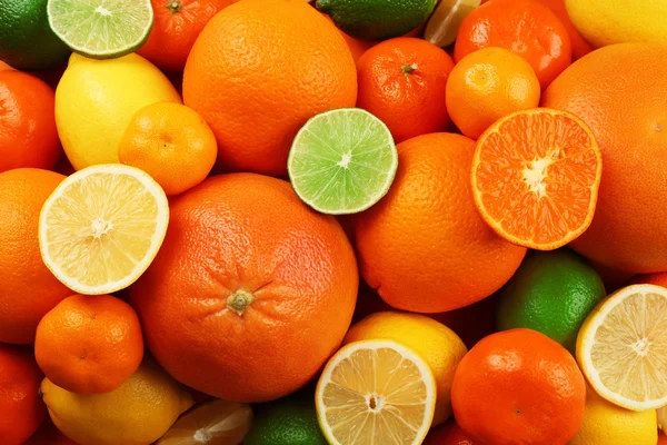Um monte de citrinos mistos, incluindo limões, limas, toranja e tangerinas com fatias, vista superior — Fotografia de Stock