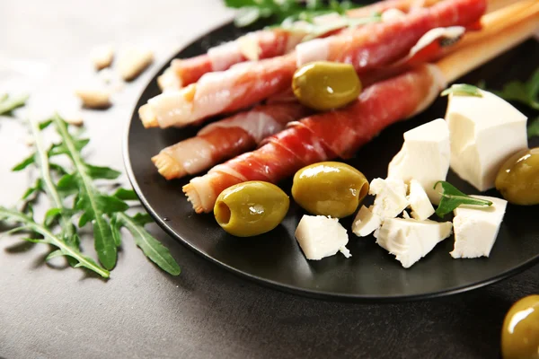 Palitos de pan grissini con jamón de jamón jamón en un plato, de cerca — Foto de Stock