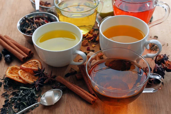 Kopjes met verschillende soorten thee en ingrediënten op tafel — Stockfoto