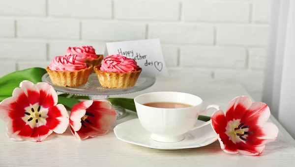 Tulipes fraîches avec cupcakes et tasse de thé — Photo