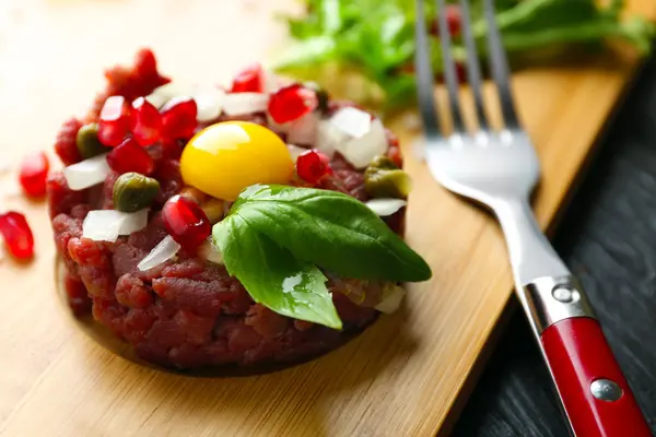 Beef tartare served on a wooden board, close up — Stock Photo, Image