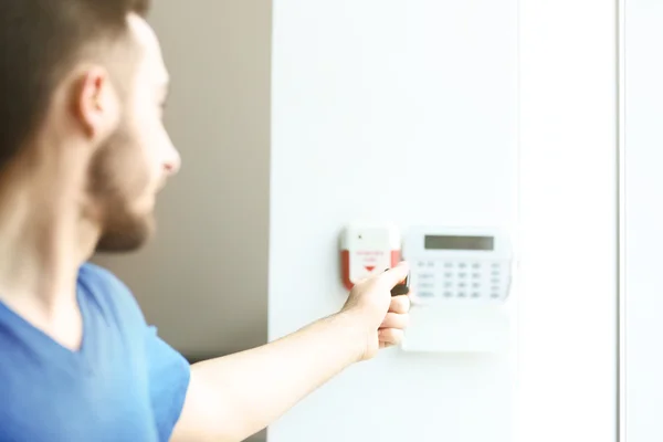 Man entering code on security system keypad indoors