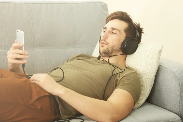 Pojken lyssnar musik liggande på soffan — Stockfoto