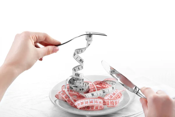 Knife and fork on plate with measuring tapes — Stock Photo, Image