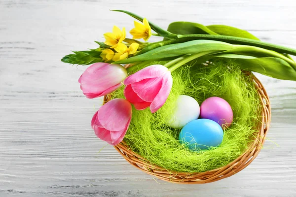 Easter eggs in nest with spring flowers — Stock Photo, Image