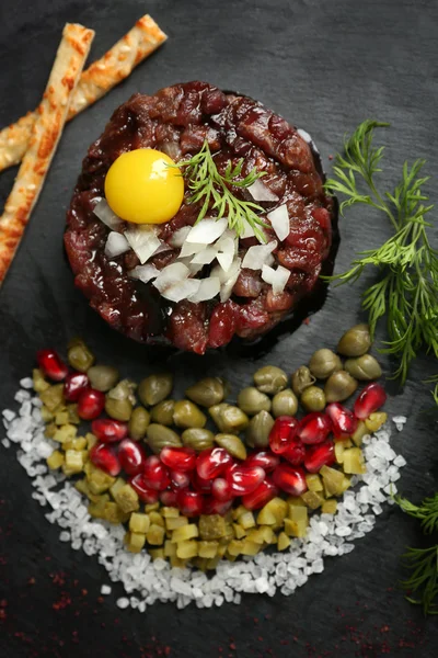 Delicioso tártaro de ternera con ingredientes sobre fondo oscuro —  Fotos de Stock