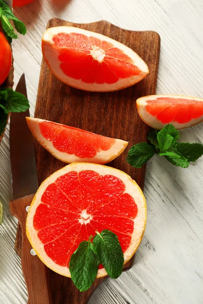 Stukken van grapefruit op houten snijplank — Stockfoto