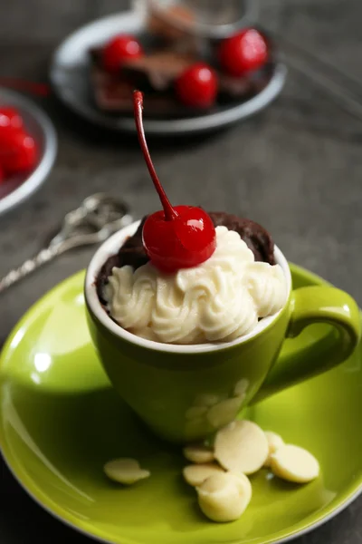 Pastel de chocolate en una taza verde servido con dos platos de cerezas y chocolates, de cerca —  Fotos de Stock