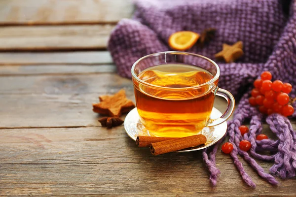 Glass cup of tea, purple blanket and herbs on wooden background — Stock Photo, Image