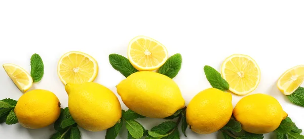 Citrons jaunes colorés tranchés et coupés en deux avec des brins de menthe isolés sur un fond blanc, vue de dessus — Photo