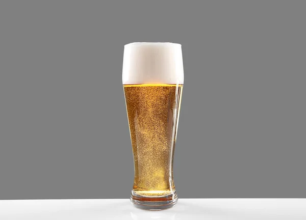 Glass of lager beer on grey background — Stock Photo, Image