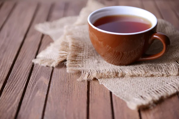 Šálek čaje na dřevěný stůl s detailním pytloviny — Stock fotografie