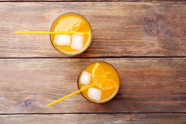 Portakal suyu buz blokları ve tübül ahşap arka plan üzerinde gözlük — Stok fotoğraf
