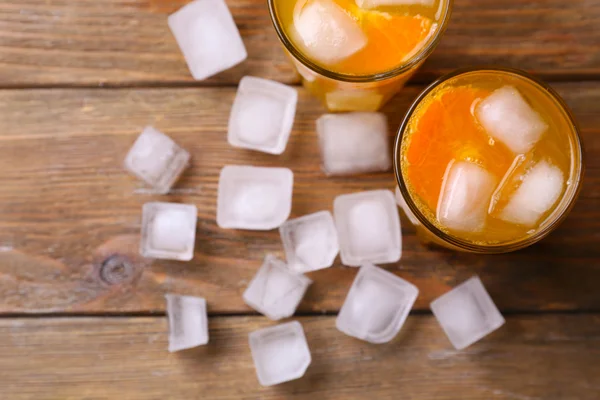 Vasos de jugo de naranja con bloque de hielo sobre fondo de madera —  Fotos de Stock