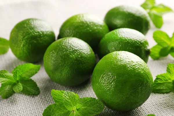 Limes and mint on wooden table — Stock Photo, Image