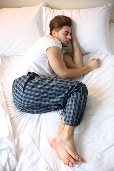 Junger Mann schläft im Bett — Stockfoto