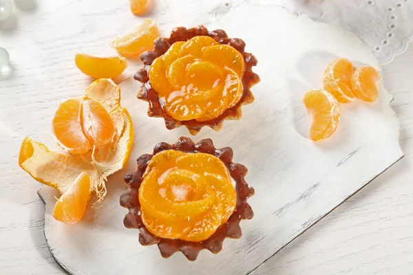 Sweet cakes with tangerines on table, close up — Stock Photo, Image