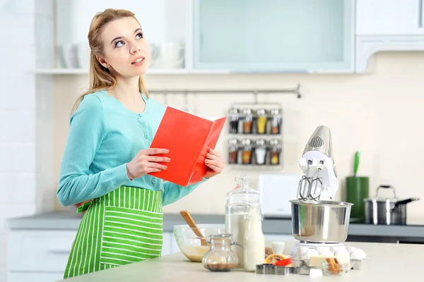 Woman using a notebook to follow a recipe — Stock Photo, Image