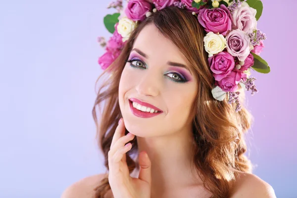 Çiçek kafa bandı mor bir arka plan üzerinde giyen güzel genç kadın — Stok fotoğraf