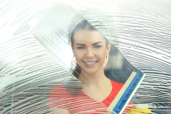 Jonge vrouw vensterglas wassen met spons mop binnen — Stockfoto