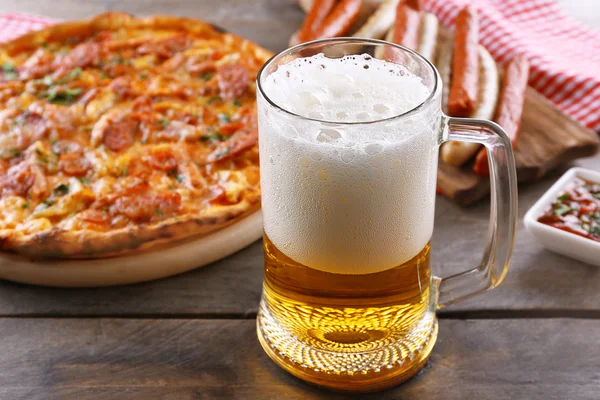 Grillwürste, leckere Pizza und ein Glas Bier auf einem Holztisch, aus nächster Nähe — Stockfoto