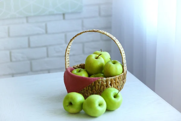 Maçãs verdes maduras em cesta em uma mesa de cozinha — Fotografia de Stock