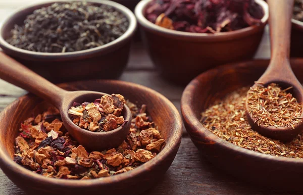 Variedad de té en tazones de barro con cuchara sobre mesa de madera, de cerca —  Fotos de Stock