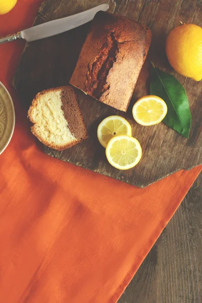 Leckeres süßes Kuchenbrot mit Zitronen auf Holzschneidebrett, Draufsicht — Stockfoto