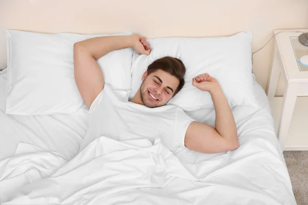 Mladý muž táhnoucí se na posteli — Stock fotografie