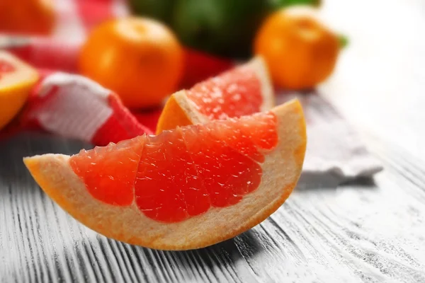 Piece of grapefruit on wooden light background — Stock Photo, Image