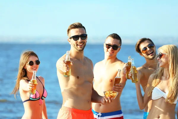 Счастливые друзья пьют пиво на пляже — стоковое фото